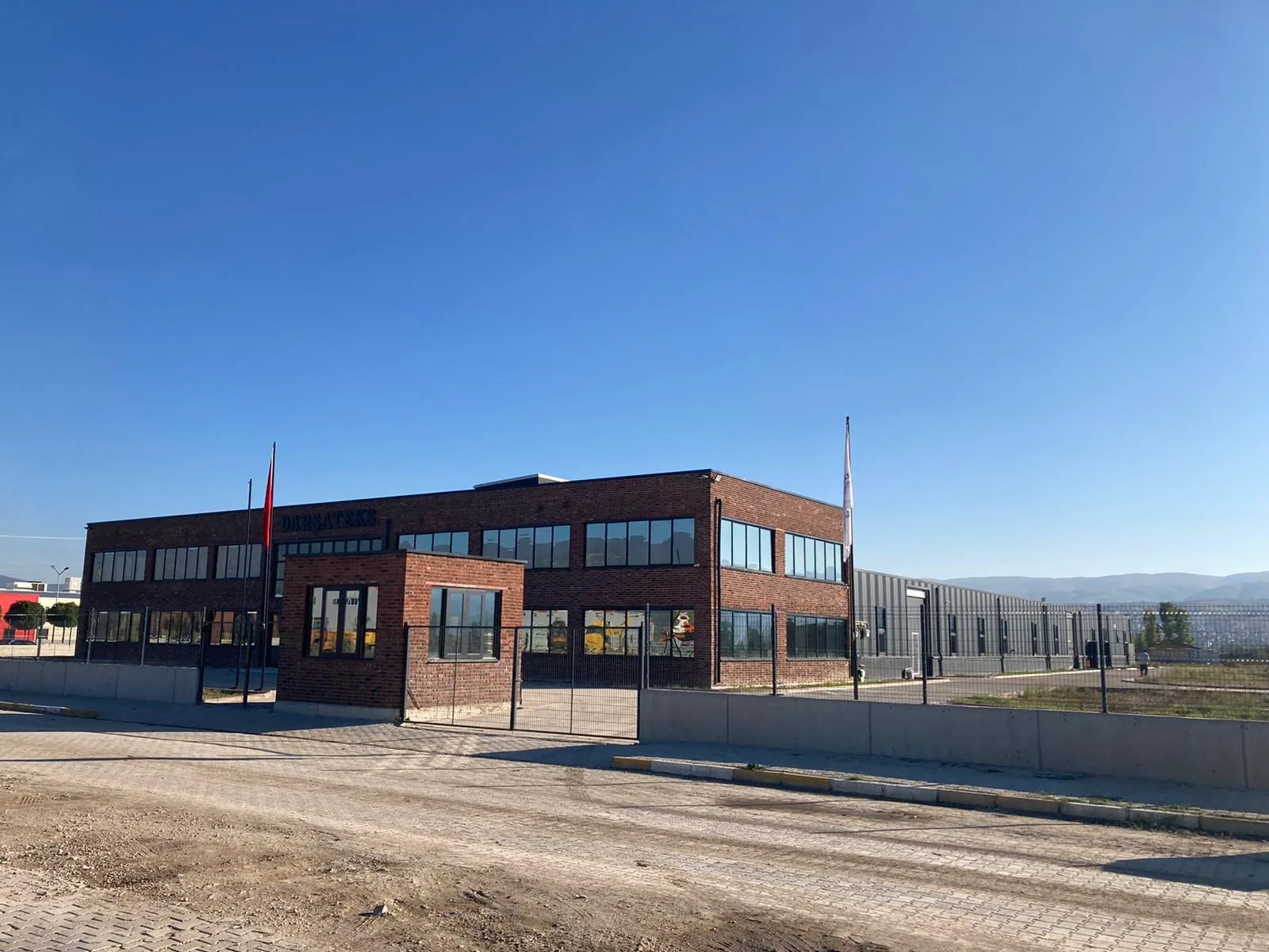 2021'de koyu mavi gökyüzü altında Erbaa'daki yeni kırmızı tuğlalı Darsateks fabrikası ve giriş binası