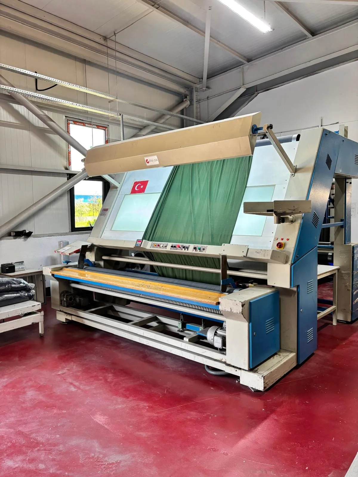 Erbaa fabrikasında ışıklı kumaş kontrol makinesinden geçen yeşil bir kumaş topu